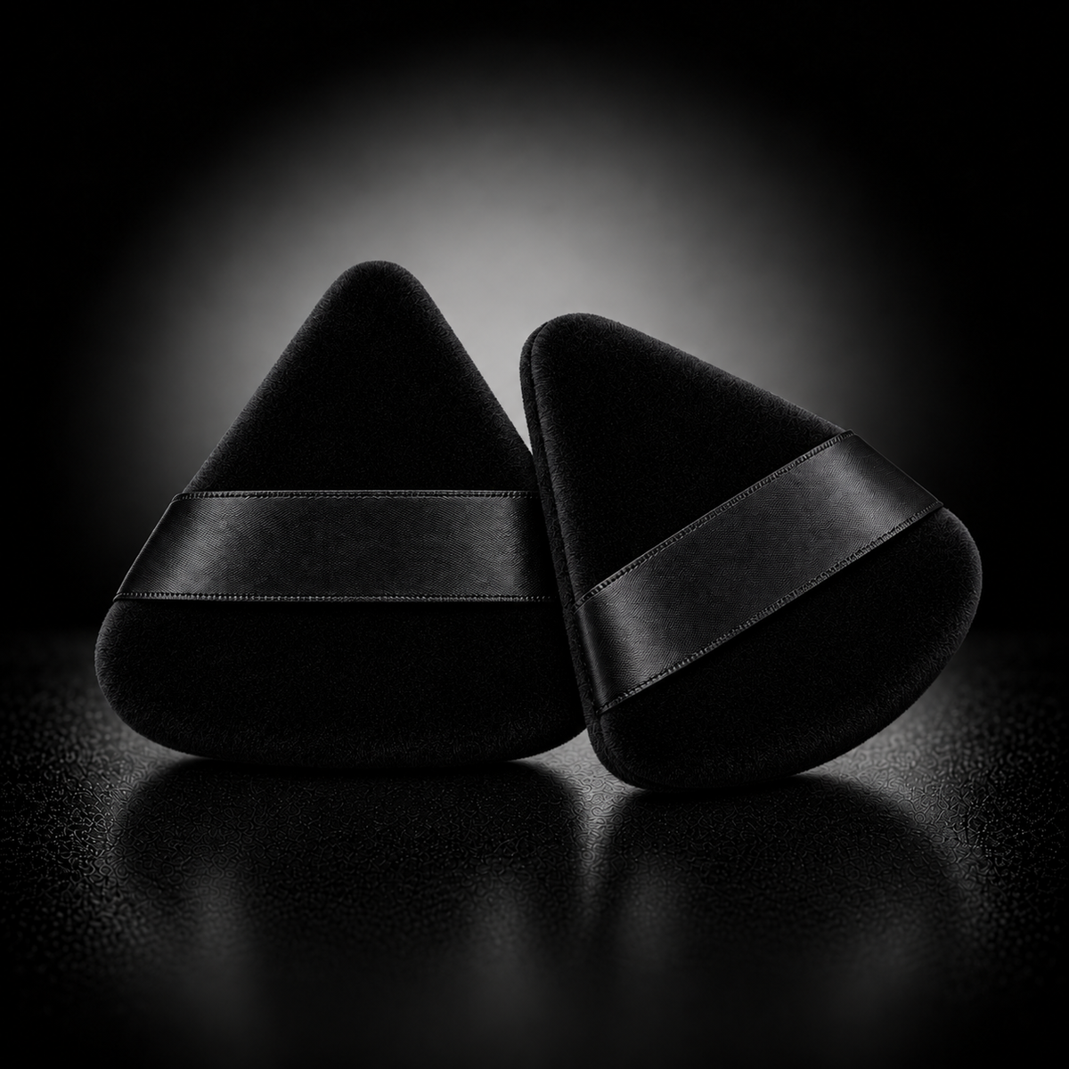 Two black triangular velour powder puffs with plain black satin finger bands
