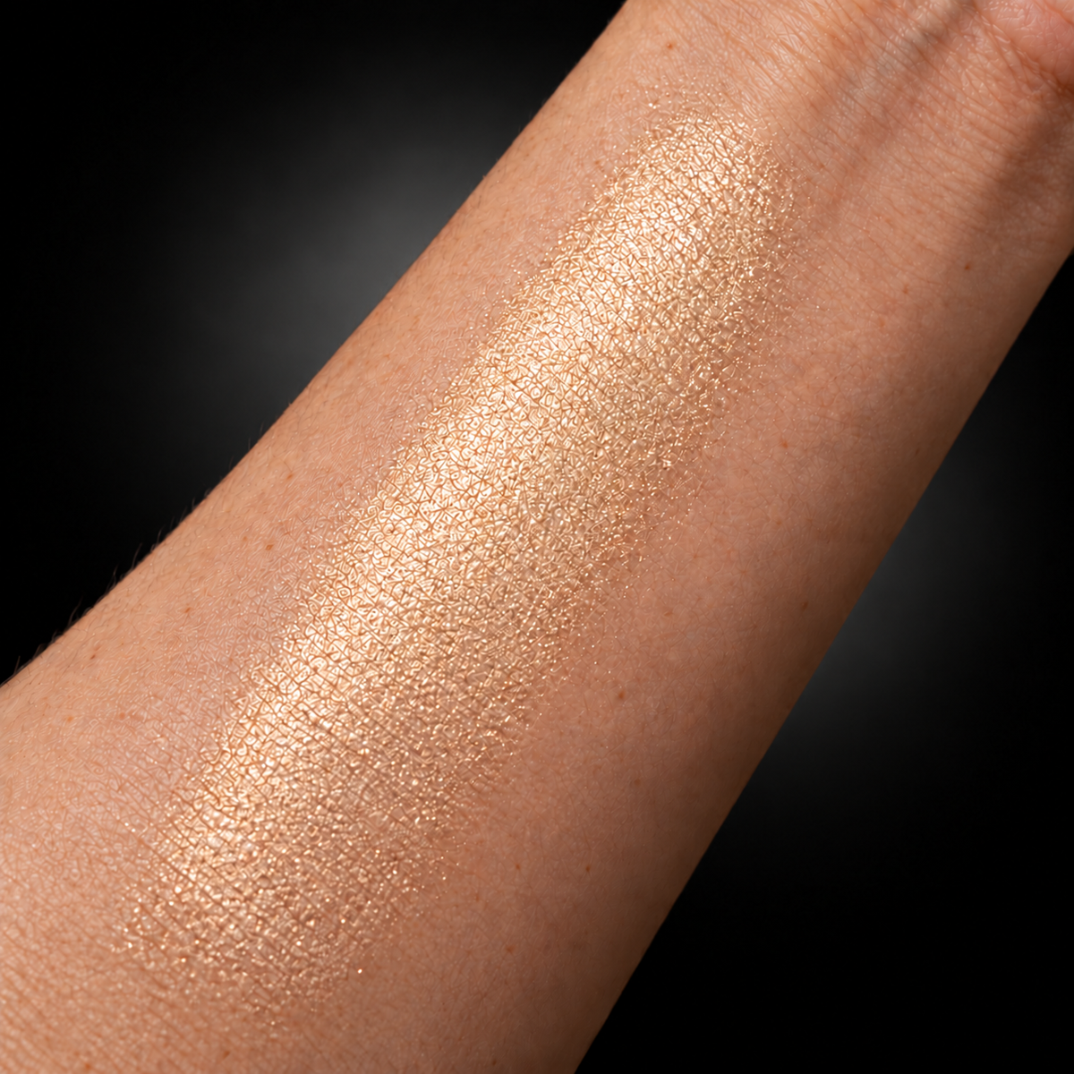 Naked Glow champagne illuminator swatched on light skin with soft neutral halo